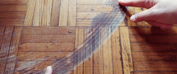 Old, scratched parquet flooring needs maintenance. the parquet is damaged by scratches from prolonged use. Master's hands show damage to the floor.
