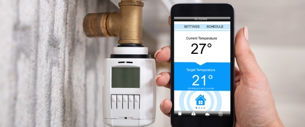 Person Using Cellphone To Adjust Temperature Of Thermostat