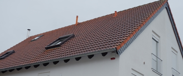 Low angle view of a house with windows on the roof under a cloudy sky